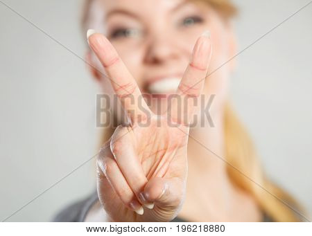 Celebration communication success concept. Cheerful lady makes v gesture. Young girl showing peace sign victory symbol.