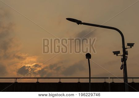 Silhouette LED Light poles and cctv on an Expressway with orange cloudy sky background ;Bangkok thailand.