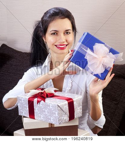 Young happy woman smiling and holds blue gift box in hands