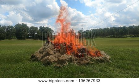 Pile of burning hay bales in a field