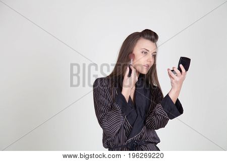 girl in coat makes brush makeup looks in the mirror 1