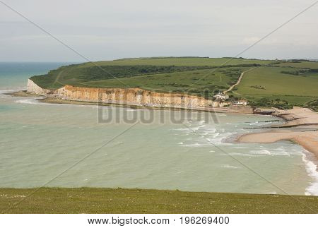 River Cuckmere shingle beach and chalk cliffs at Cuckmere Haven near Eastbourne East Sussex England. With unrecognizable people on beach