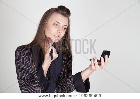 girl in coat makes brush makeup looks in the mirror 1