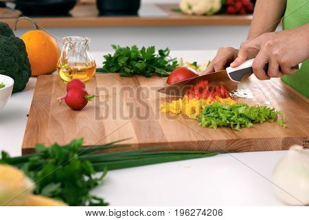 Close up of woman's hands cooking in the kitchen. Housewife slicing fresh salad. Vegetarian and healthily cooking concept.