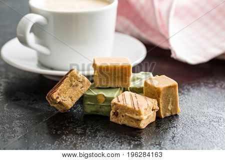 Colorful caramel candies and coffee cup on table.