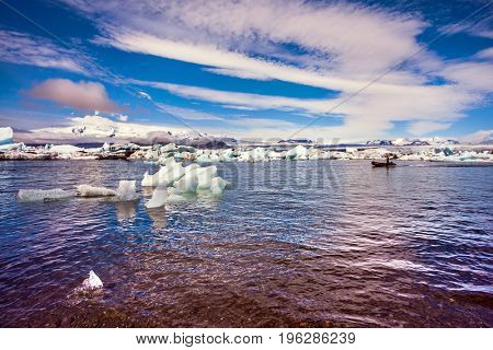 Clouds reflected in the water of lagoon. The ice floes and cirrocumulus clouds of lagoon Jokulsarlon, Iceland. The concept of northern extreme tourism