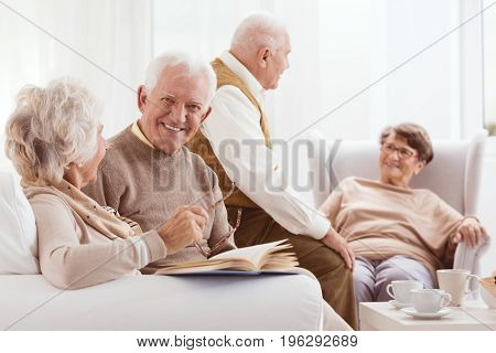 Elderly friends at resting home enjoying time drinking tee talking and reading