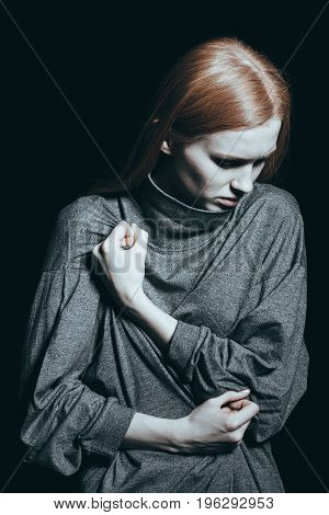 Depressed girl deep in thought holding her fist to her chest in a concept of abuse