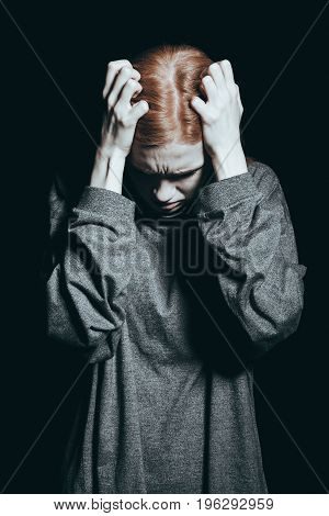 Young girl at the brink of sanity holding her head in her hands