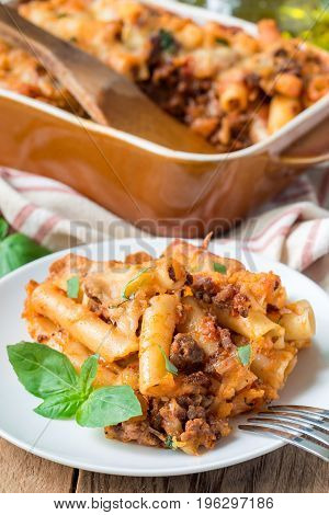 Ziti bolognese on a white plate pasta casserole with minced meat tomato sauce and cheese vertical