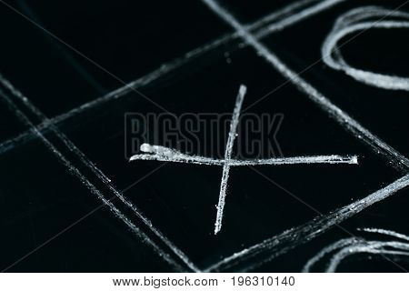 tic tac toe chalk on a a school blackboard dark.
