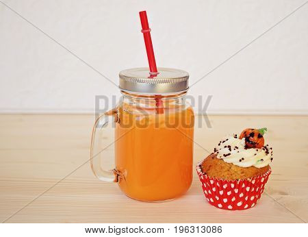 Big jar with orange juice and cupcake for halloween party. Halloween decoating concept for food