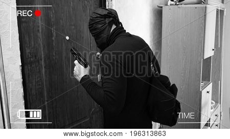 surveillance camera recorded the thief, who broke into the house with a gun, carrying a bag with the loot.