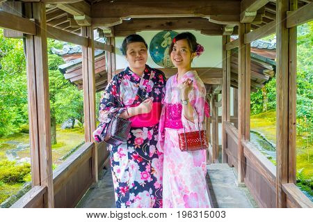 KYOTO, JAPAN - JULY 05, 2017: Two beatiful Japanesse girls posing for camera in Hojo Hall of Tenryu-ji in the Arashiyama district of Kyoto.