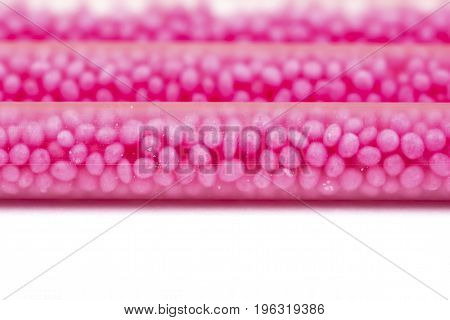 Drinking straws on white background with copy space. Top view of pink eco-friendly straws wiht strawberry balls for summer cocktails.