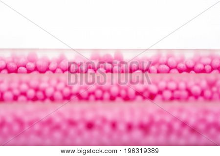 Drinking straws on white background with copy space. Top view of pink eco-friendly straws wiht strawberry balls for summer cocktails.