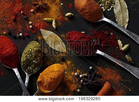 Spices on spoons on a black background shot from above