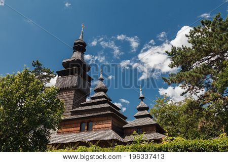 Old wooden Lemk church against a bright blue sky with clouds. Culture of Ukraine