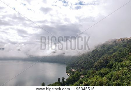 View of the slopes, forests and houses of Lake Albano on a cloudy and foggy day. Albano is a quiet and bucolic countryside region near Rome. Located in the Lazio region, central Italy