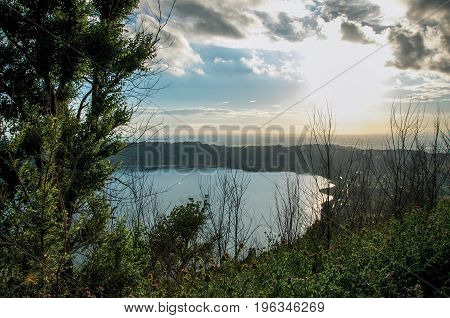View of the slopes, forests and hills of Lake Albano in a cloudy sunset. Albano is a quiet and bucolic countryside region near Rome. Located in the Lazio region, central Italy