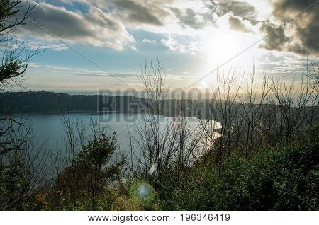 View of the slopes, forests and hills of Lake Albano in a cloudy sunset. Albano is a quiet and bucolic countryside region near Rome. Located in the Lazio region, central Italy. Retouched photo