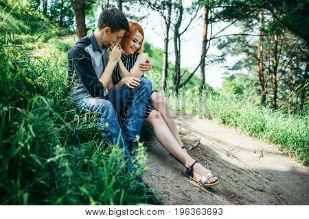 portrait of beautiful young pair in a park sitting on the ground