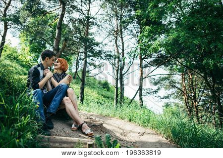 portrait of beautiful young pair in a park sitting on the ground