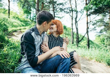 portrait of beautiful young pair in a park sitting on the ground