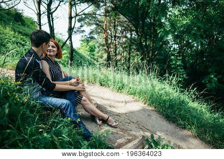 portrait of beautiful young pair in a park sitting on the ground