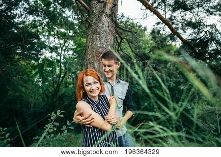 Love couple kissing under a tree, readhead girlfriend