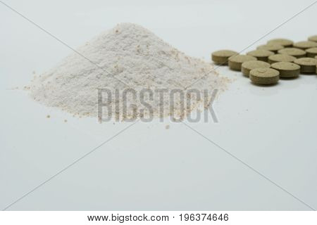 Herbal tablets and dry powder on white background