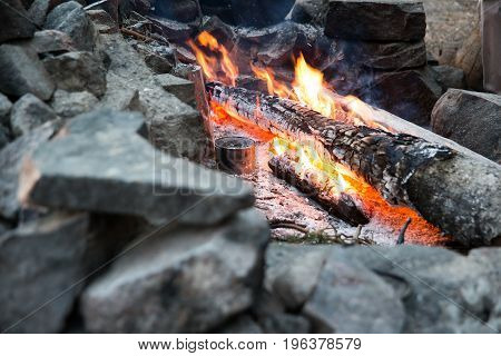 A bonfire with cobs with a can in the stones in the afternoon