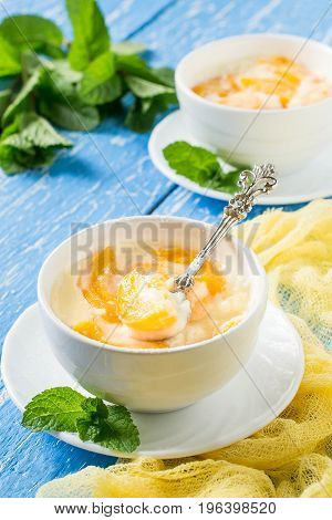 Delicious creamy apricot dessert in white cups on yellow napkin. Summer dessert with fruits. Dietary and healthy food. Vertical