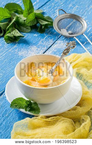 Delicious creamy apricot dessert in white cup on yellow napkin. Sieve with powdered sugar. Summer desserts with fruits. Dietary and healthy food. Vertical