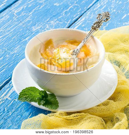 Delicious creamy apricot dessert in white cup on yellow napkin. Summer desserts with fruits. Dietary and healthy food. Square image