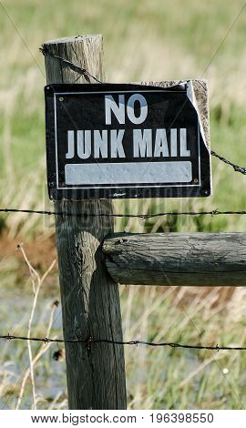 Metal sign on wooden fence warning no junk mail