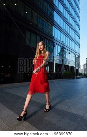 Beautiful blonde lady in red dress on White Square office center in Moscow Russia