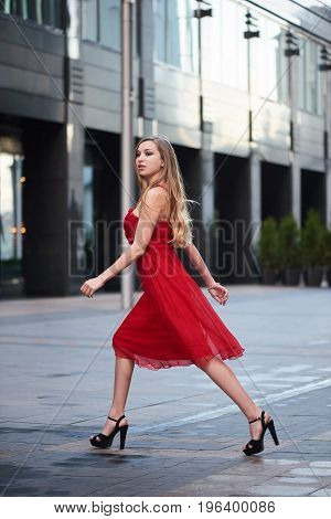 Beautiful blonde lady in red dress on White Square office center in Moscow Russia