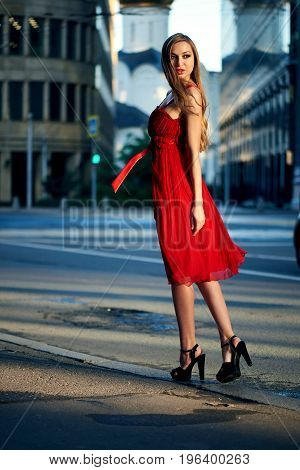 Beautiful blonde lady in red dress on White Square office center in Moscow Russia