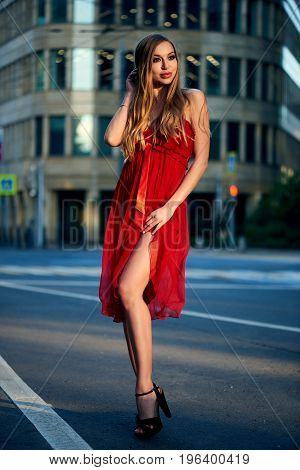 Beautiful blonde lady in red dress on White Square office center in Moscow Russia