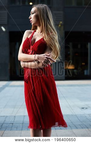 Beautiful blonde lady in red dress on White Square office center in Moscow Russia