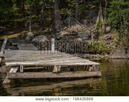Old wodden pier leading in dark finnish forest