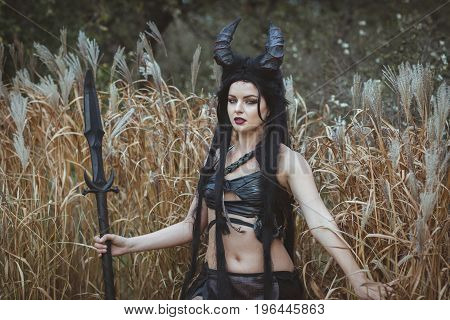 Portrait of a girl with horns stands in the thickets