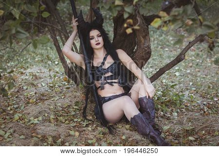 Girl with horns sits under a tree