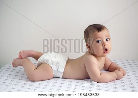 naked baby in diapers lying on her belly on the diaper with stars