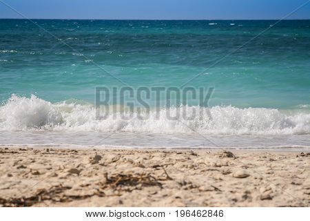 Wave breaking on the beautiful white beach of Baru island