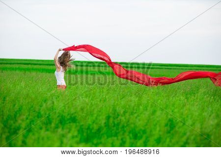 Young lady runing with tissue in green field. Beautiful happy woman walking  in the summer rural meadow. Outdoor summer portrait of pretty sport style woman jumping with fabric. Beautiful fit tan girl. Sexy slim model caucasian ethnicity outdoors.