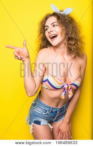 Young Beautiful Curly Woman  Pointed On Side With Happy Fency Mood On Yellow Background