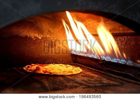 pizza prepares in old stove near fire