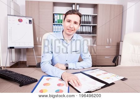 Man in his offce with charts folders on table. Finance and corporate